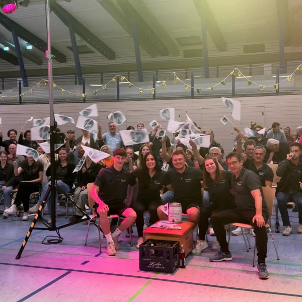 G’winnsch gege d’Musik 2026: Unser Team mit dem Fanblock auf der Tribüne